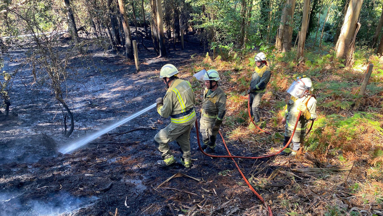 Operarios trabajando en la extinción del incendio en O Con do Navío, A Illa de Arousa. JOSÉ LUIZ OUBIÑA